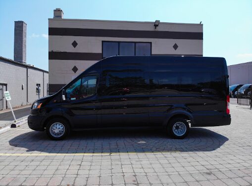 Black rental mini van parked near a scenic Michigan lakeshore, ready for exploration.