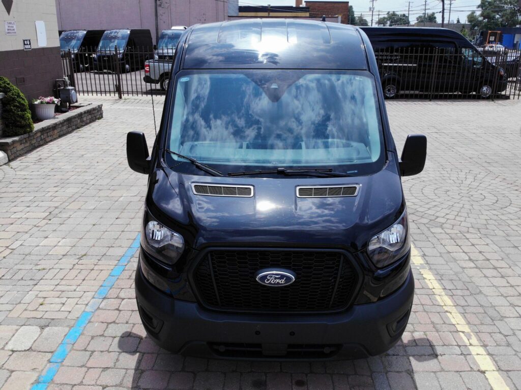 The image shows the front view of a black Ford van with a visible grille and windshield