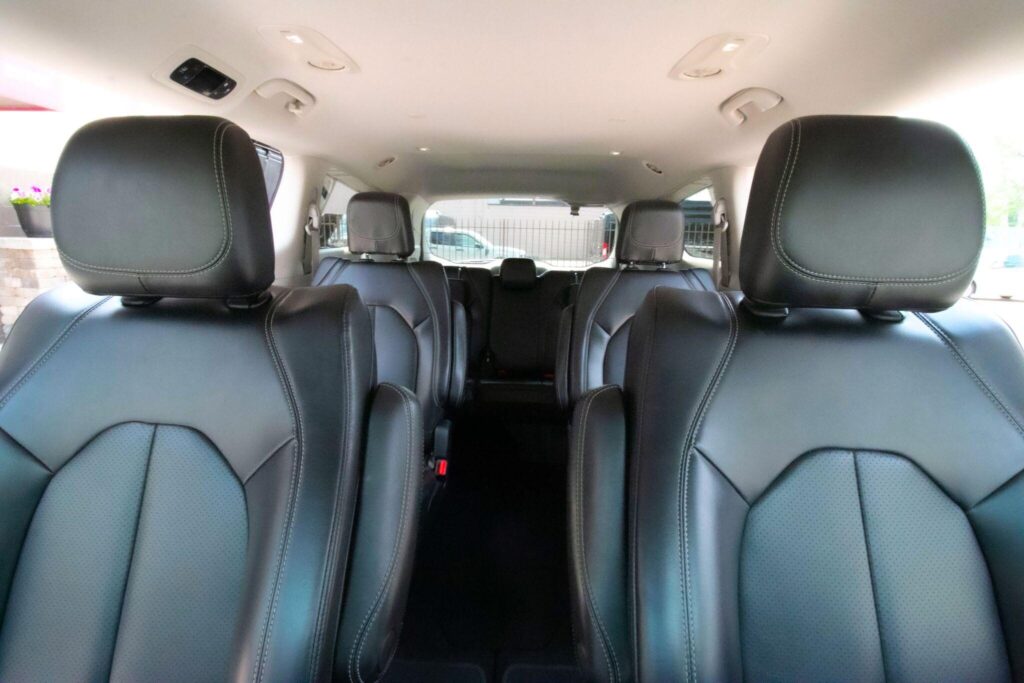 The image shows the interior of a vehicle with black leather seats arranged in rows