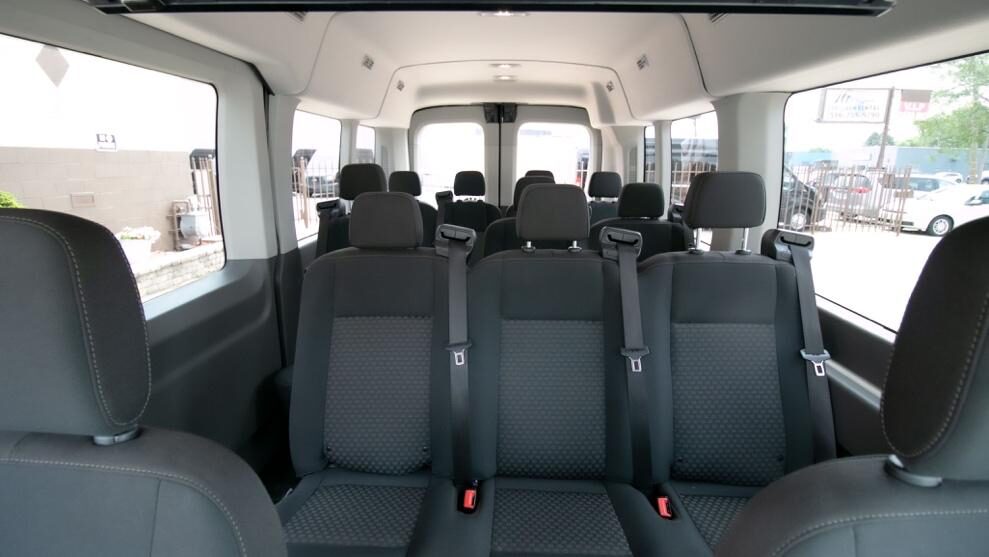 Black 12-passenger van with university sports team loading equipment