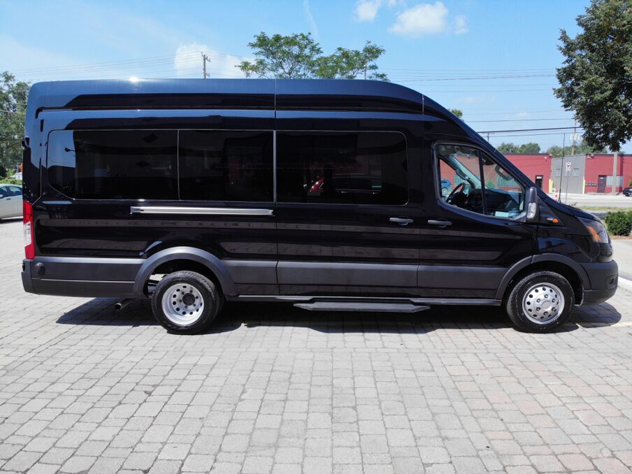 Black Mercedes Sprinter 15-passenger van driving along a scenic Michigan highway for group trave