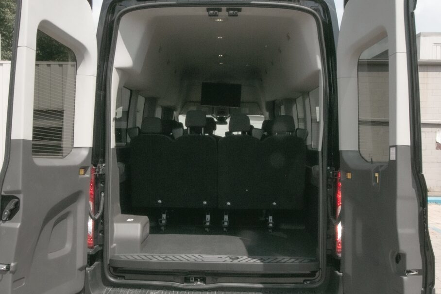 A family and business team loading luggage into a black passenger van at Detroit Metro Airport, prepared for Michigan travel