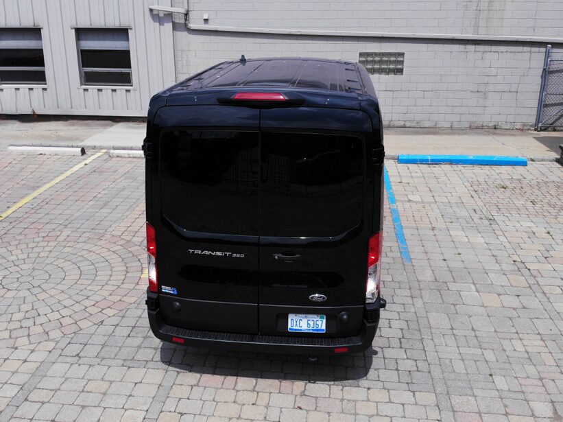 Black 12-passenger van ready for pickup at Detroit Metro Airport parking lot, highlighting self-service airport rental