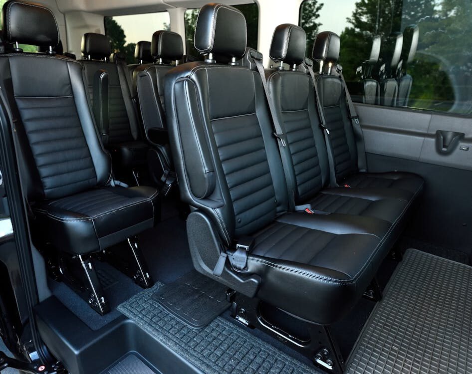 Interior of a spacious black passenger van with multiple rows of seating for group travel