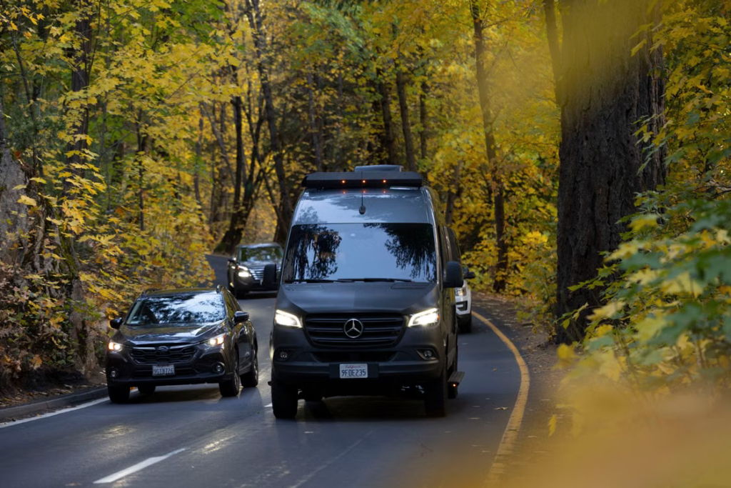 Black passenger van traveling along a Michigan road during early fall