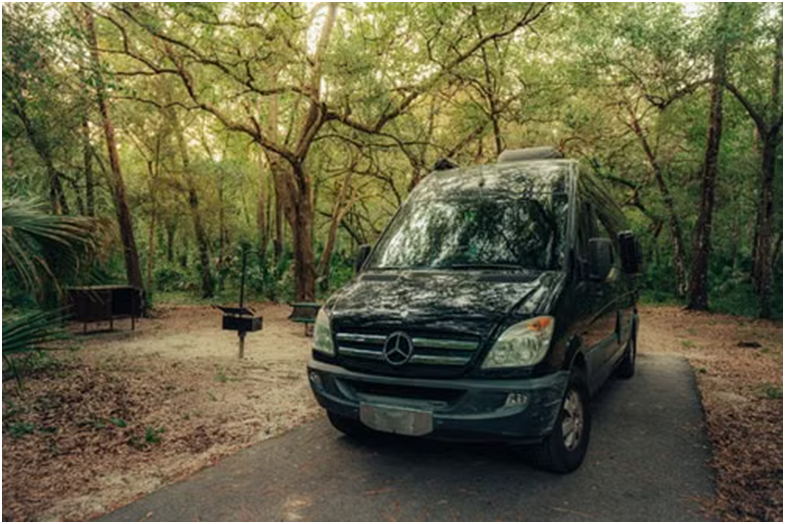 A black passenger van parked beside autumn trees during a family weekend trip