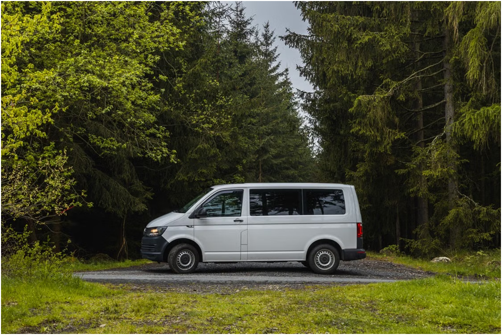 A passenger van parked near a tree-lined road